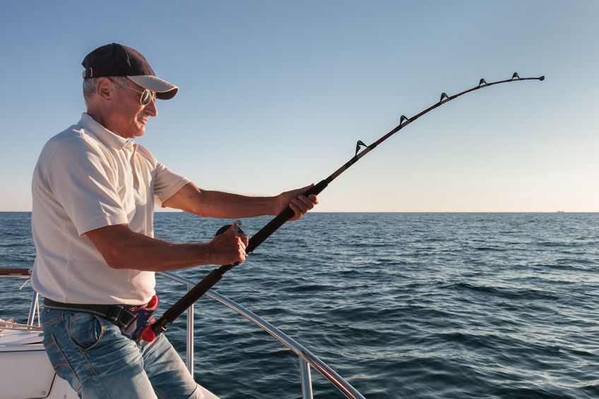 Man on a boat reels in a fish