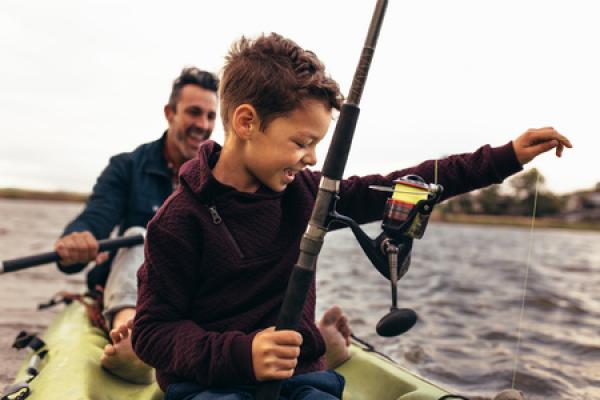 A man fishes in a boat with his son