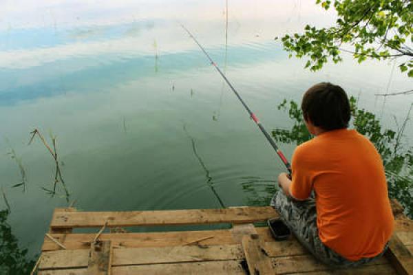 A young man fishes off a dock using a lightweight rod