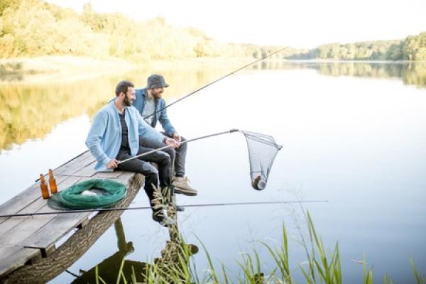 Two men sit together on a dock, fishing together