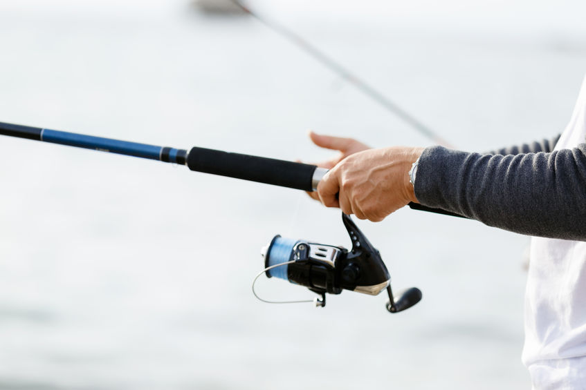 A close up of a man's hand holding a fishing rod